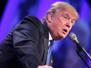 Donald Trump beugt sich mit verzogenem Mund über ein Rednerpult-Mikrofon