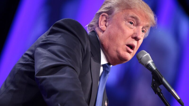 Donald Trump beugt sich mit verzogenem Mund über ein Rednerpult-Mikrofon