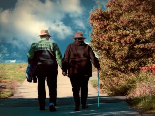 Symbolbild: Älteres Paar spaziert Hand in Hand einen Weg entlang
