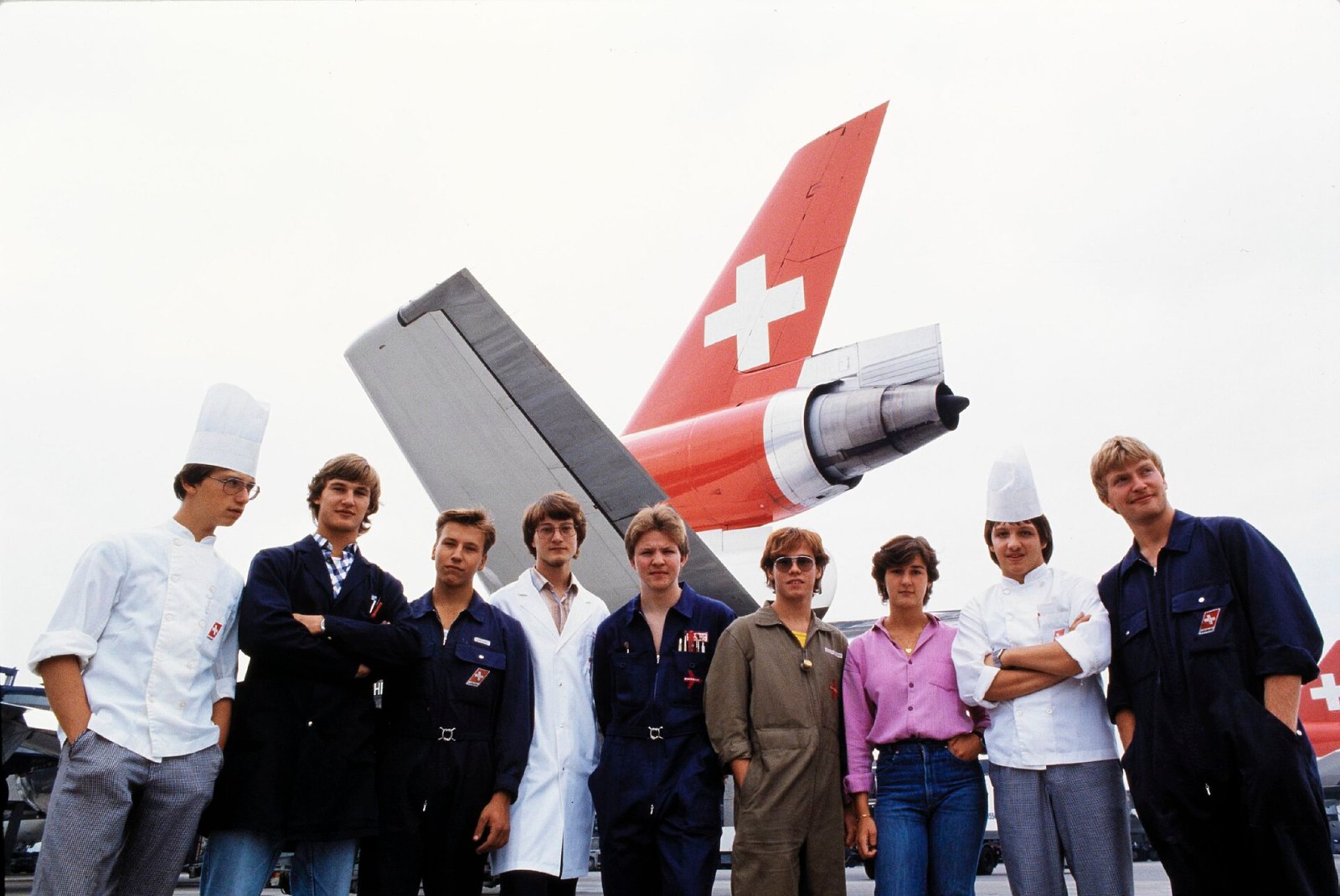 Archivbild um 1990: Gruppenaufnahme von Swissair-Lernenden vor dem Heck eines Flugzeugs in Zürich-Kloten