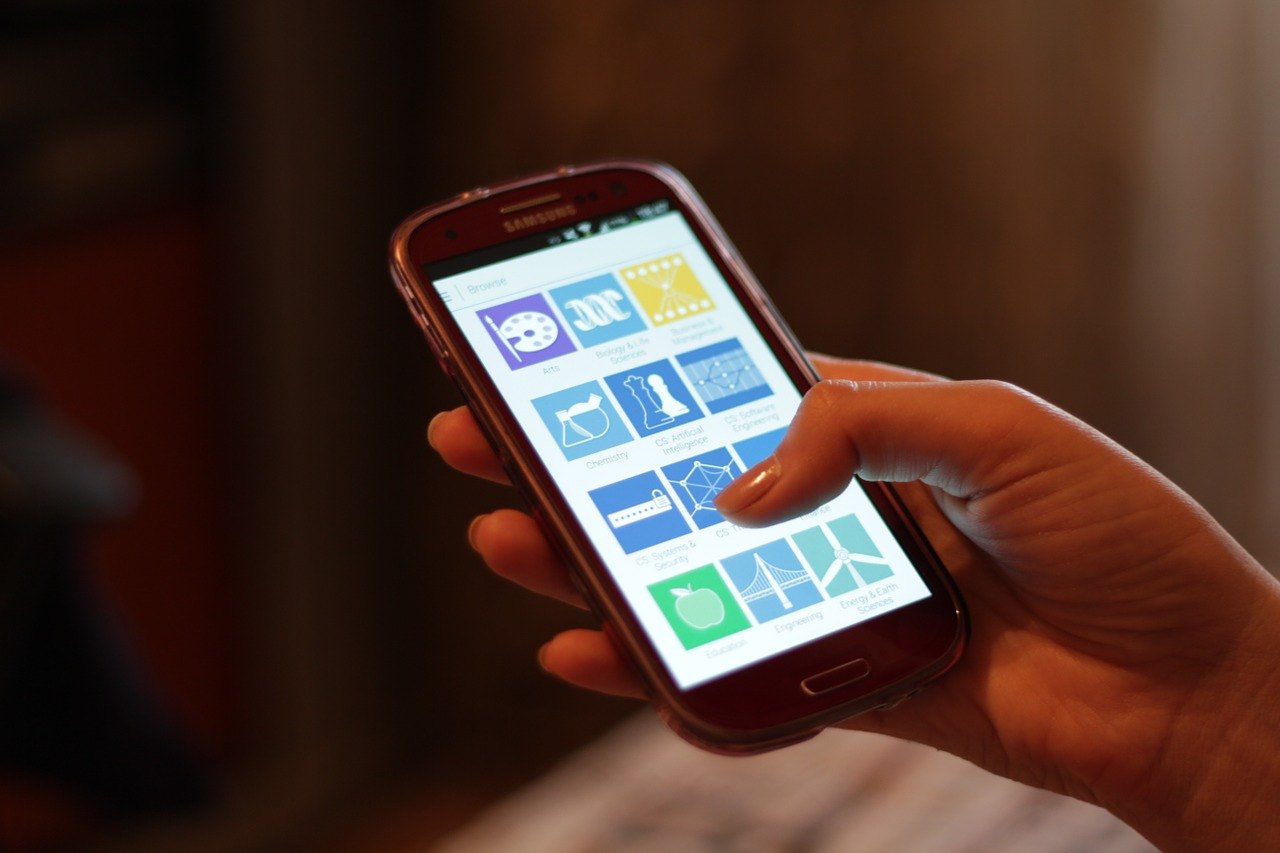 Hände halten ein Smartphone mit App-Symbolen